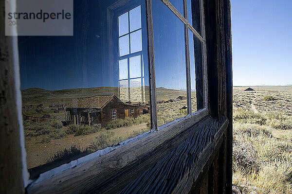 Looking into a building window reflecting the ghost town of Bodie  CA.