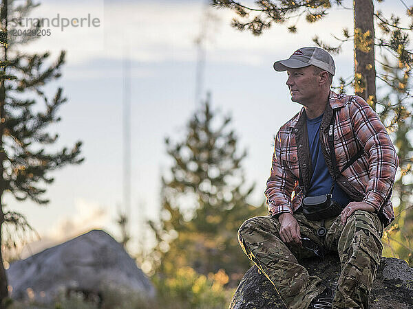 Man with binoculars resting on rock after hiking  McCall  Idaho  USA