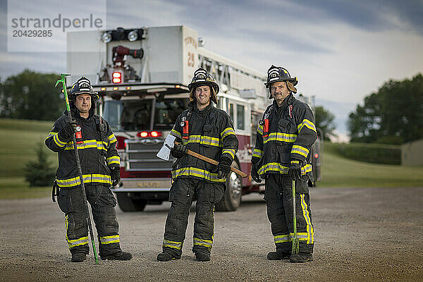 Family of firefighters posing against fire engine  New Holstein  Wisconsin  USA