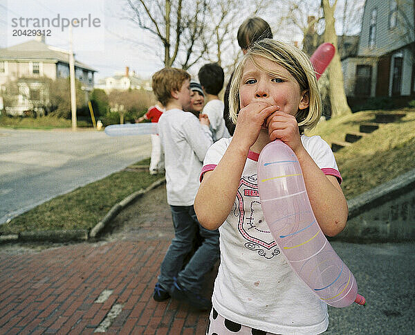 young girl blows up balloon