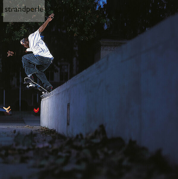 Skateboarder grinds on stone ledge