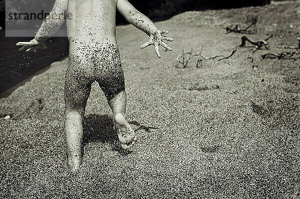 A sandy bottomed toddler runs along the shore of Lake Taupo  New Zealand.