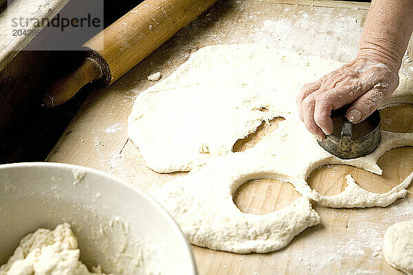 Woman pressing biscuit cutter  preparing to bake biscuits.