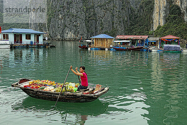 A fruit vendor paddles boxes of product in Halong Bay  Vietnam.