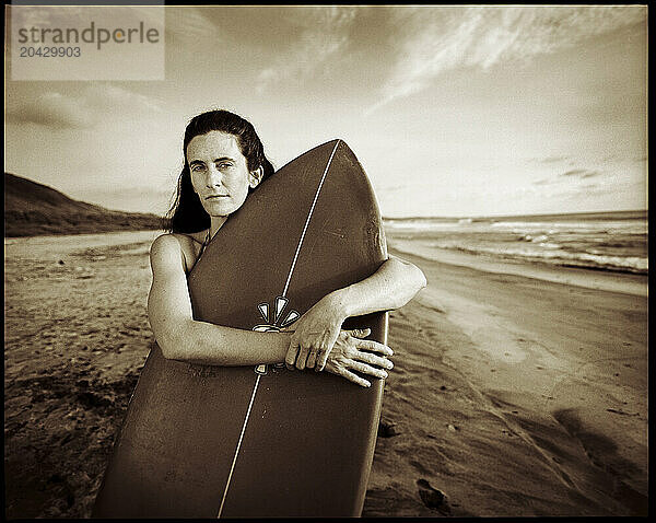 A young woman holds a surfboard on the beach in Michoacan  Mexico