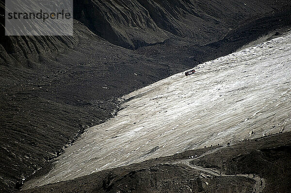 A glacier bus heads down a glacier in the Columbia Icefield as tourists hike the path to its toe in Jasper National Park  Alberta Canada on 7/30/2010