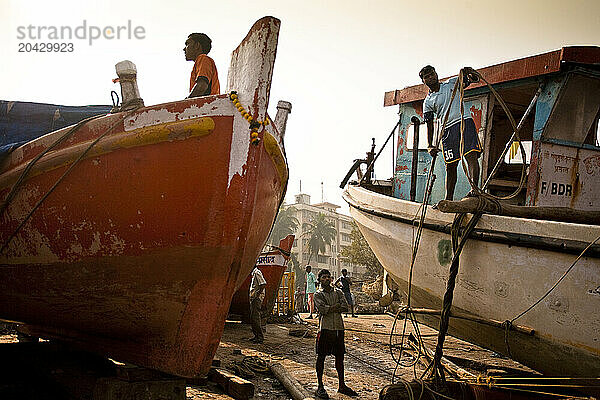 Three fishermen prepare their fishing boats.