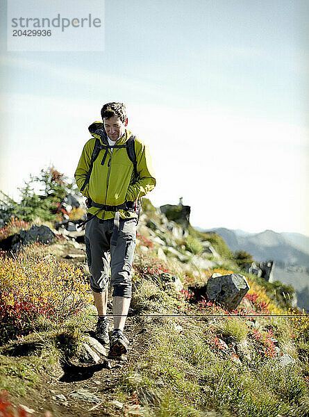 A male hiker walks along a ridge on top of a mountain