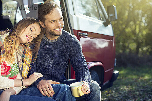 The young couple is spending time in the wooded area with the Caravan