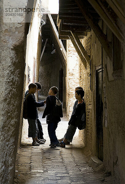 School boys gather in a narrow walkway to talk after school in Fez  Morocco. (Backlit)