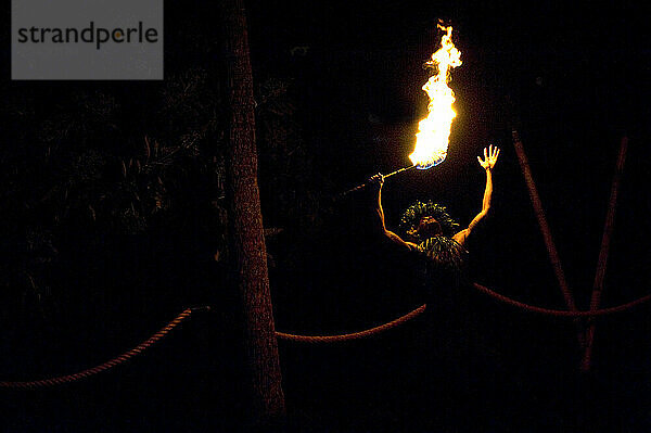 A male fire dancer in traditional dress at a Luau on the Kona Coast of Hawaii on 3/12/2010