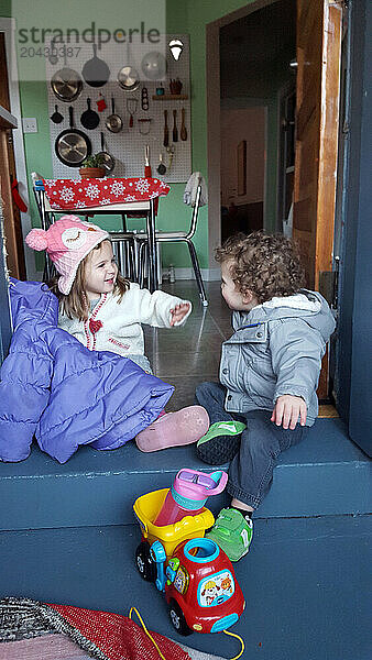 Siblings laughing on their way outside.