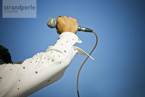 Elvis impersonator hold up the mic during a performance.