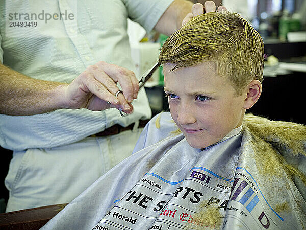 boy gets hair cut at barber shop