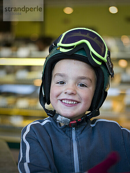 boy in a ski helmet smiles in a cafe