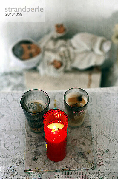 Candles burn beside a baby Jesus doll in a small roadside capilla.