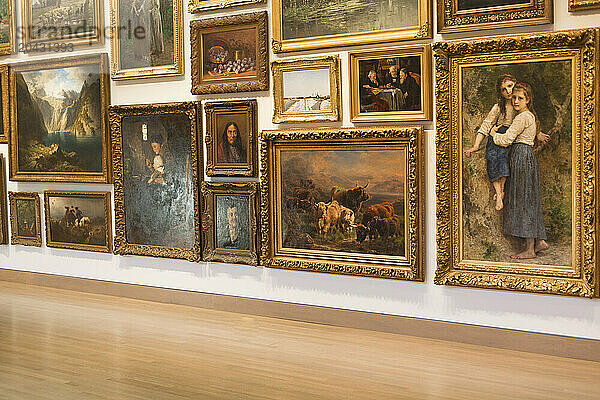 A wall of classical oil paintings in a museum.