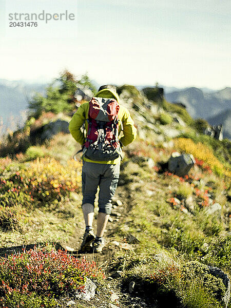 A male hiker walks along a ridge on top of a mountain