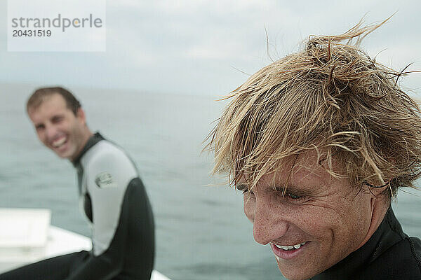 Men laugh after a dive on a boat.