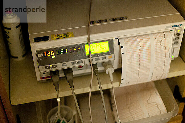 A fetal heart rate monitor glows in the maternity ward of a hospital.