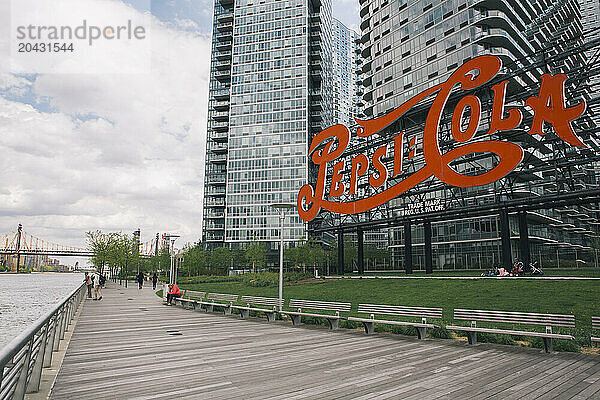 People on promenade boardwalk near iconic sign in Gantry Plaza State Park  Long Island City  New York City  USA