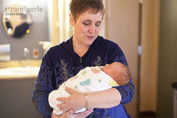 A woman holds a newborn baby in the maternity ward of a hospital.