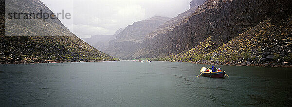 A wooden dory moves downstream on the Colorado River in Grand Canyon National Park  Arizona on a stormy day.