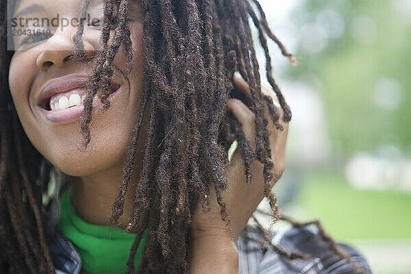 Portrait of a young woman with hair in dreads  in a city park.