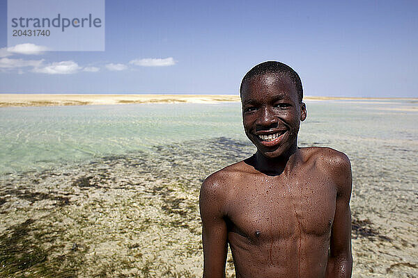 Portrait of shirtless boy standing on coastal beach and smiling  Mozambique