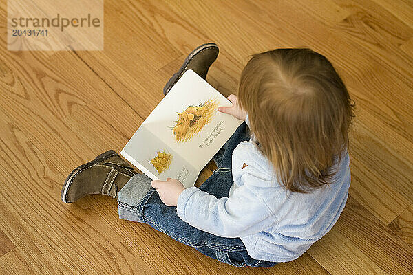 An toddler reading a book.