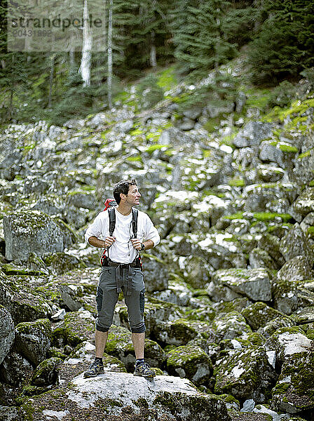 A middle aged male standing on landslide of rock partially cover with moss.