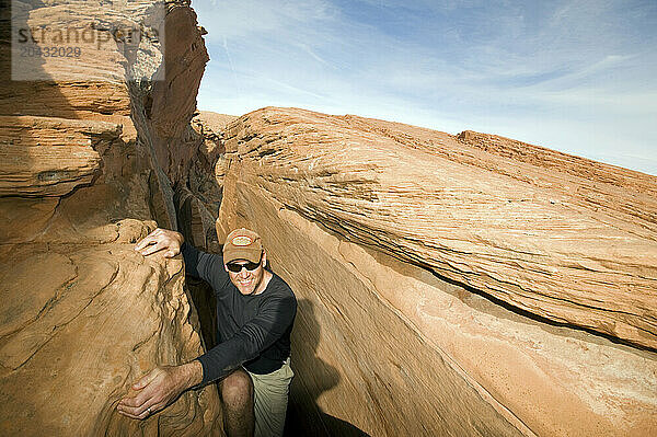 A man climbing through a cliff band in Utah's Grand Staircase/Escalante National Monument