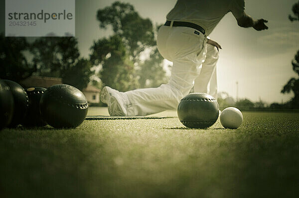 A older man outside lawn bowling.