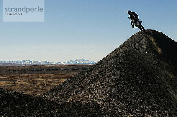 A young man jumps his dirt bike high in the air while motocross riding the surreal dunes near Cameron  AZ.