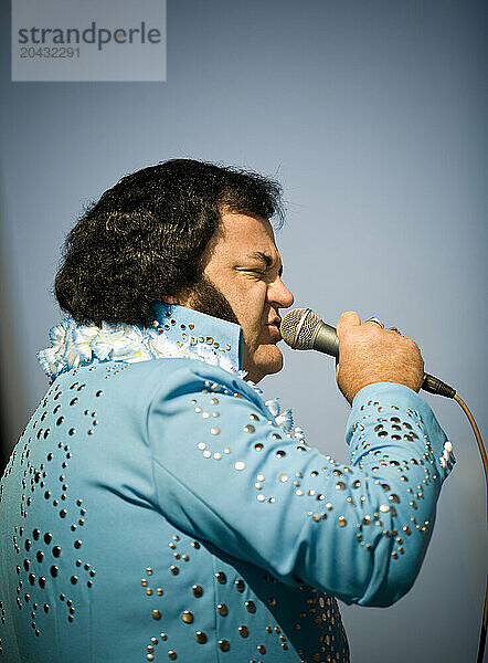 Elvis impersonator in a blue costume sings for the crowd.