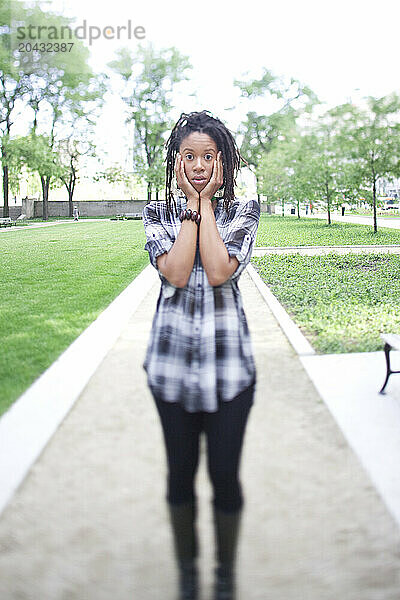 Portrait of a young woman with hair in dreads  in a city park.