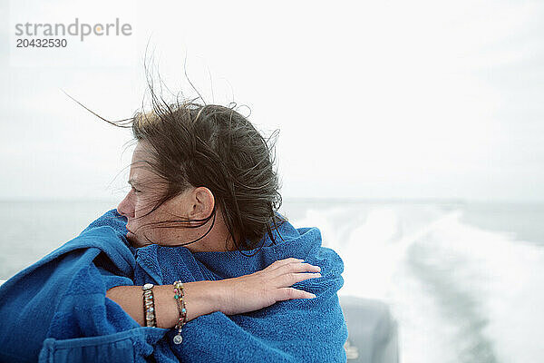 The wind whips a woman's hair around on a boat.