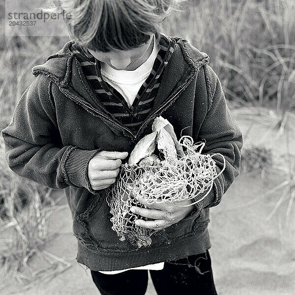 young boy with gifts from the sea found on the beach