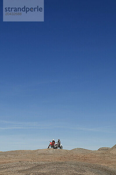 Young men take a break from riding dirt bikes during a motocross trip to the surreal dunes of the Painted Desert near Cameron  AZ.