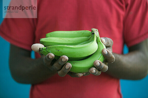 A man holding green bananas in his hands.