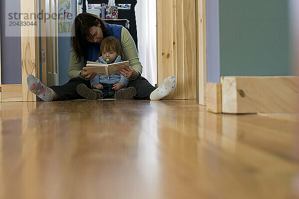 A mother reads a book to her toddler.