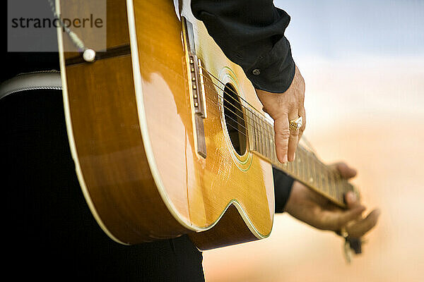 Musician playing the guitar on stage performing in front of a crowd.