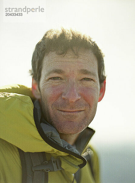 A portrait of a middle aged male hiker in a green jacket.