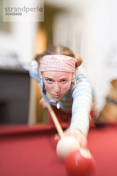 Young woman playing pool.