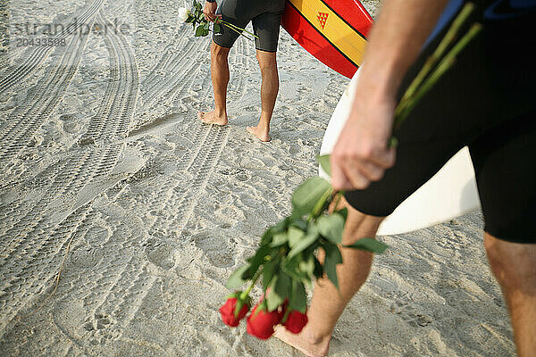 Surfers carry roses and flower petals into the ocean for a paddle out