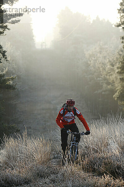 Mountain Biker Riding through Frosty Grass