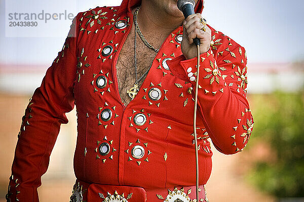 Elvis impersonator on stage performing in front of a crowd.