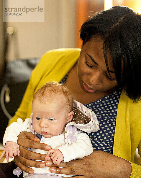 A woman holds a newborn baby in a living room.