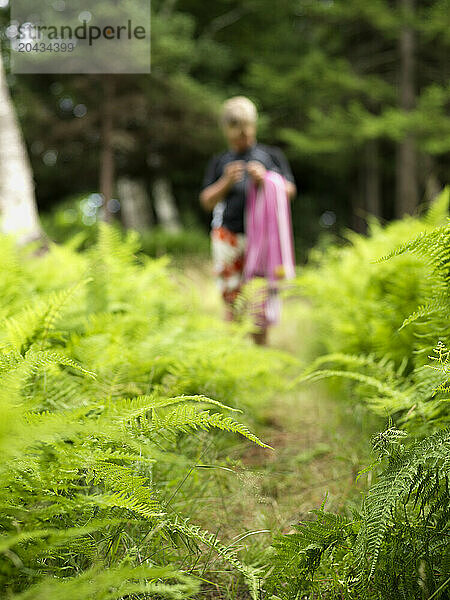 boy walks through fern field