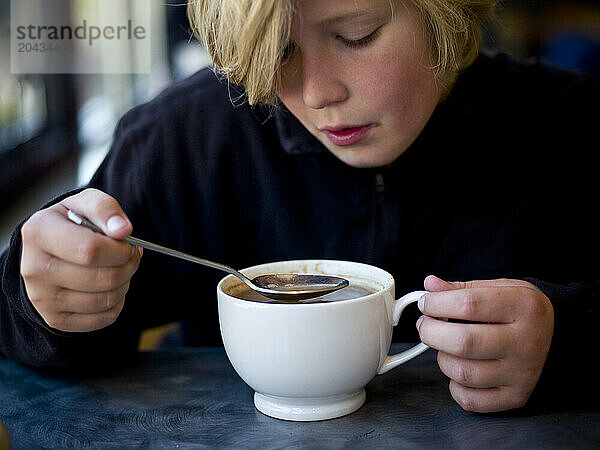 boy sips hot chocolate in a cafe